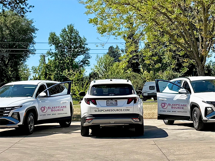 Three SleepCare Source branded cars, two with front doors open showcasing logos, and one in the center showing the company website on the rear bumper.